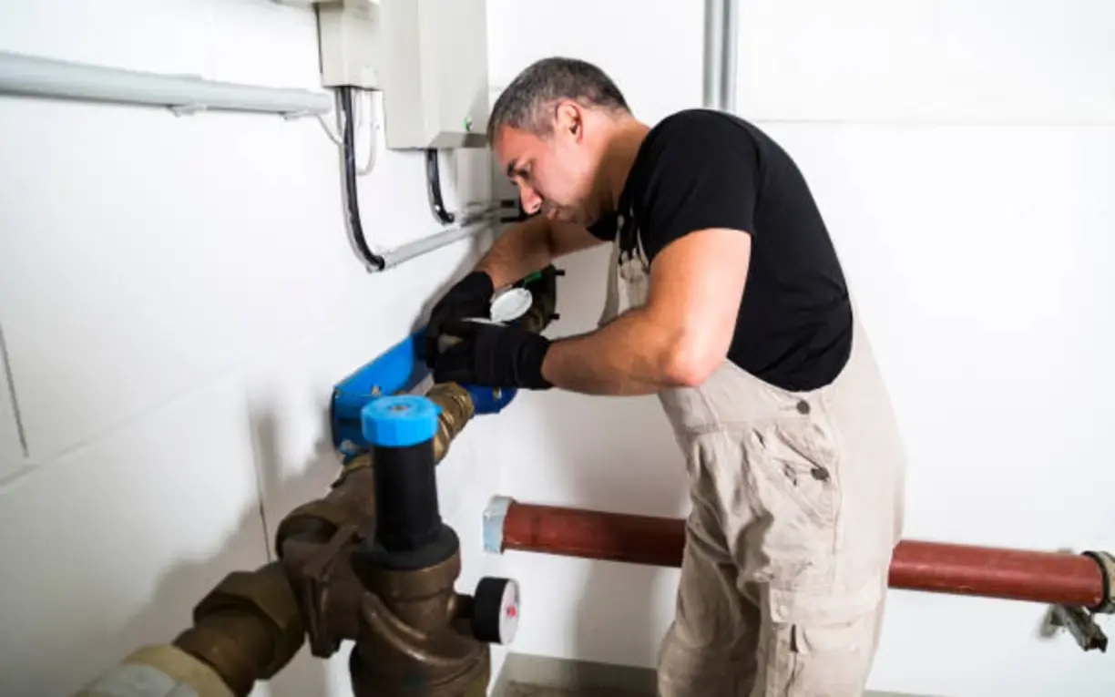 Technician servicing piping and valves in a commercial mechanical room