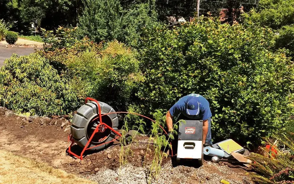 Technician operating sewer camera equipment with documentation during a residential inspection